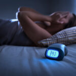 Dealing with Insomnia. Insomniac man lying in bed late in the night.
