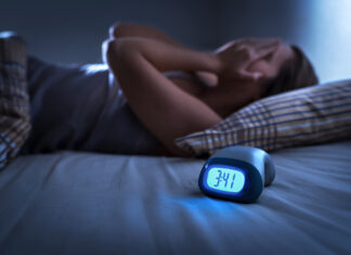 Dealing with Insomnia. Insomniac man lying in bed late in the night.