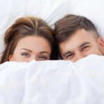 Couple Under Bed Sheets. Guide on How to Have a Better Sex.