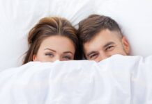 How to Be More Sexually Intimate: Guide to Rekindling the Spark (2025) Couple Under Bed Sheets. Guide on How to Have a Better Sex.