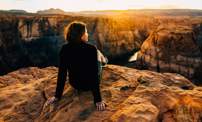Woman sitting on a cliff. Off-peak Travel