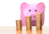 What You Should Expect from Gold Investing Companies in 2025 Piggybank with three stacks of coins. Gold Investing Companies representation
