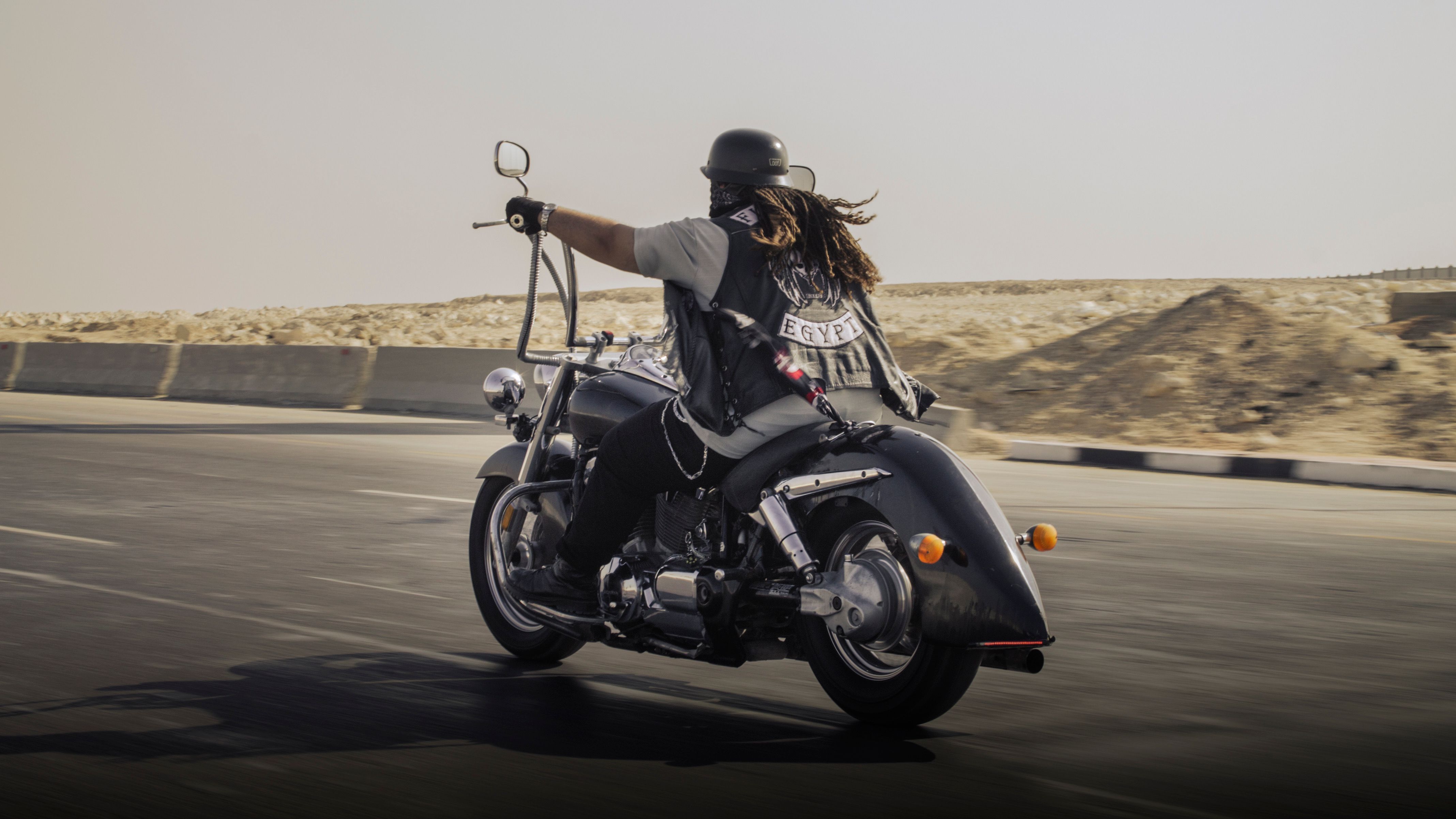 Biker in leather gear riding a motorcycle on an open desert highway