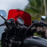 Close-up of a motorcycle handlebar area with a red tinted windshield