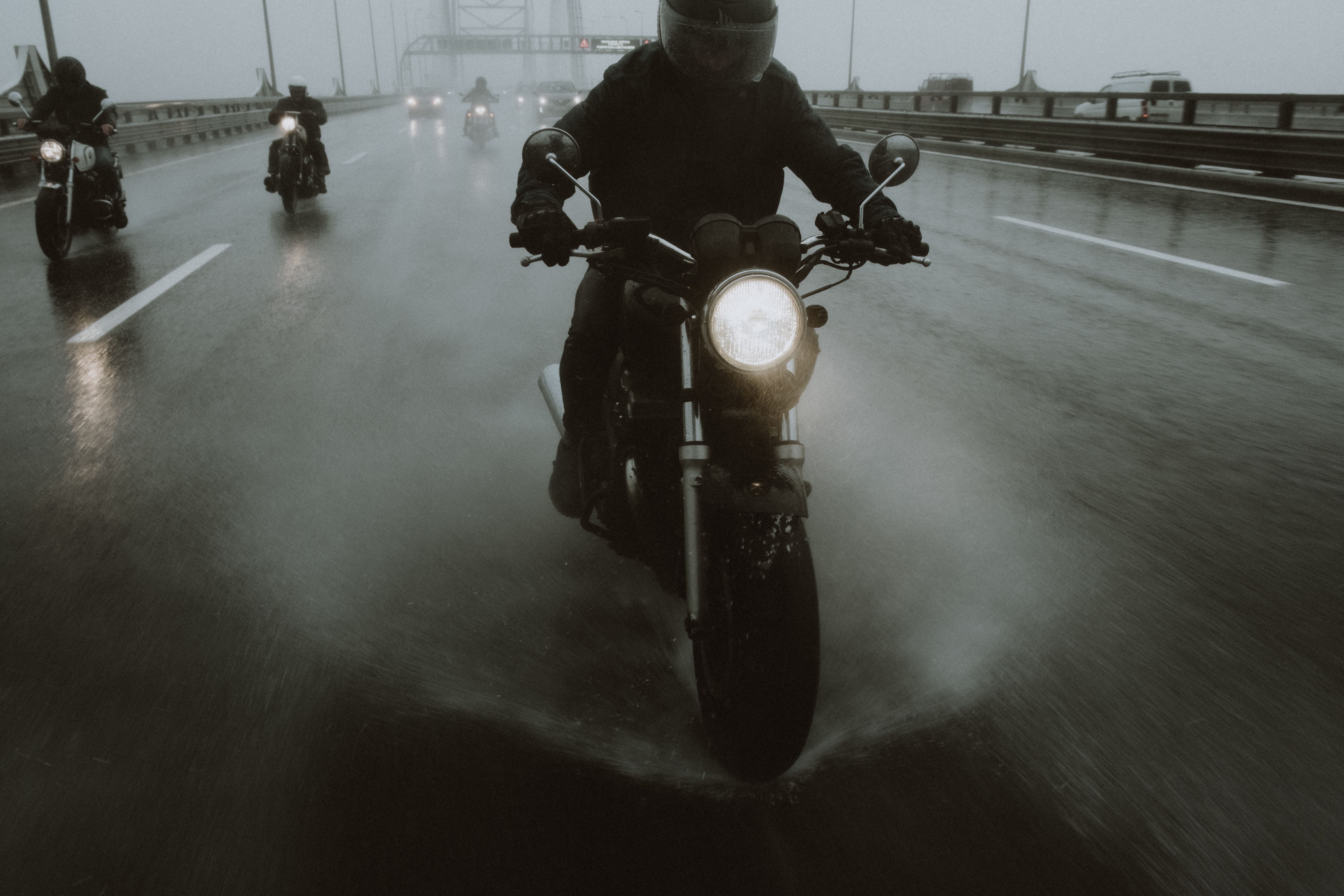Group of motorcyclists riding through heavy rain on a highway