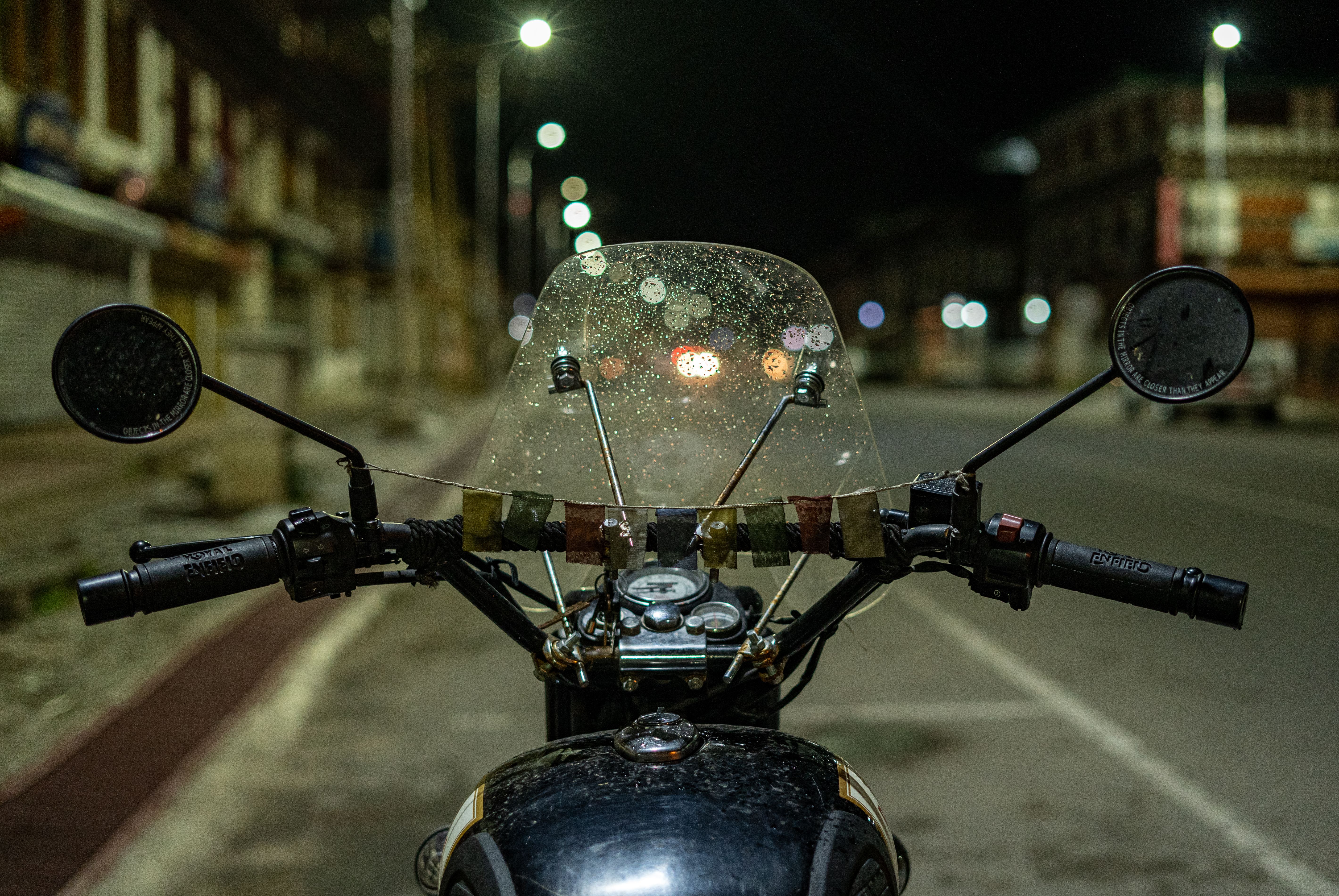 Vintage motorcycle with rain-speckled windshield on a wet city street at night